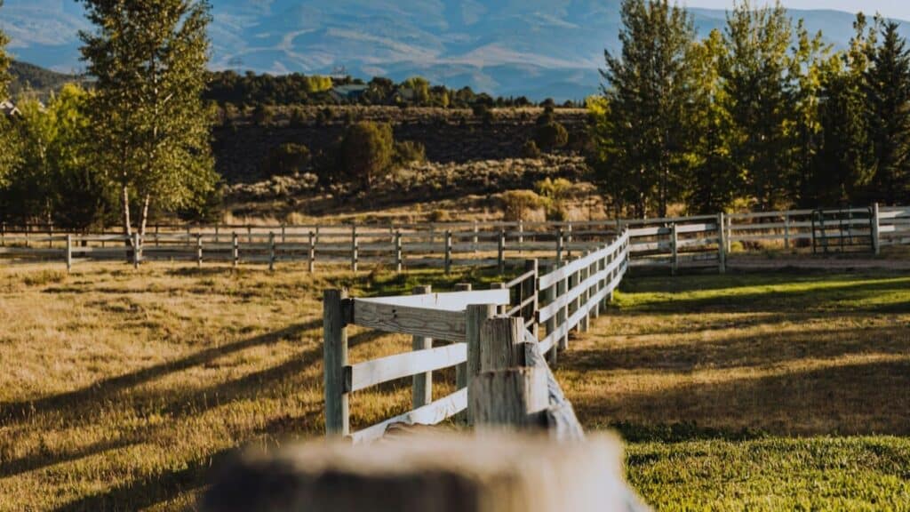 Wooden ranch fence across rural acreage with mountains in western Colorado